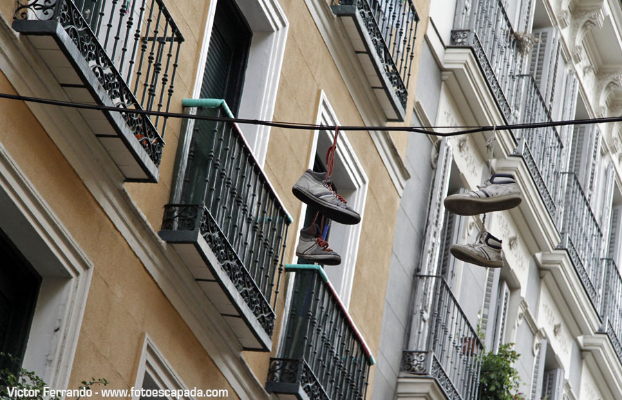 Shoeffiti arte urbano en forma de zapatillas colgadas de un cable en Madrid