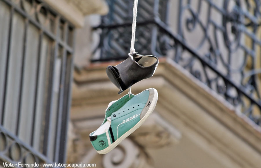 Shoeffiti arte urbano en forma de zapatillas colgadas de un cable en Madrid