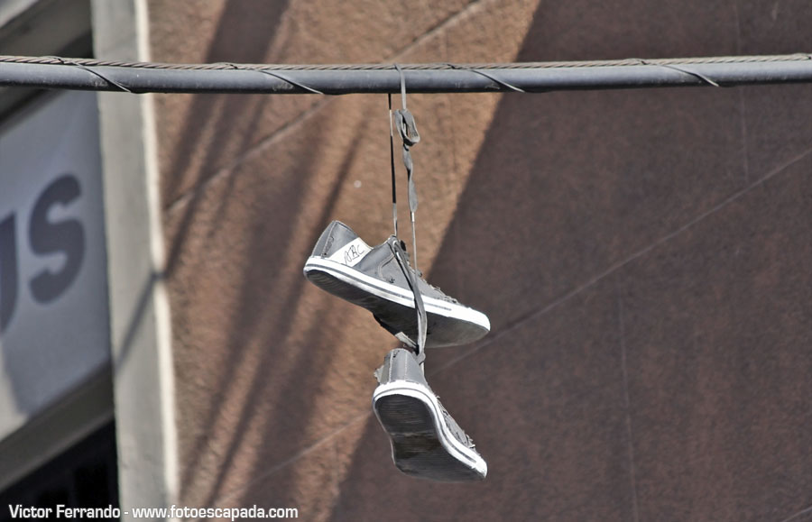 Shoefiti arte urbano en forma de zapatillas colgadas de un cable en Madrid